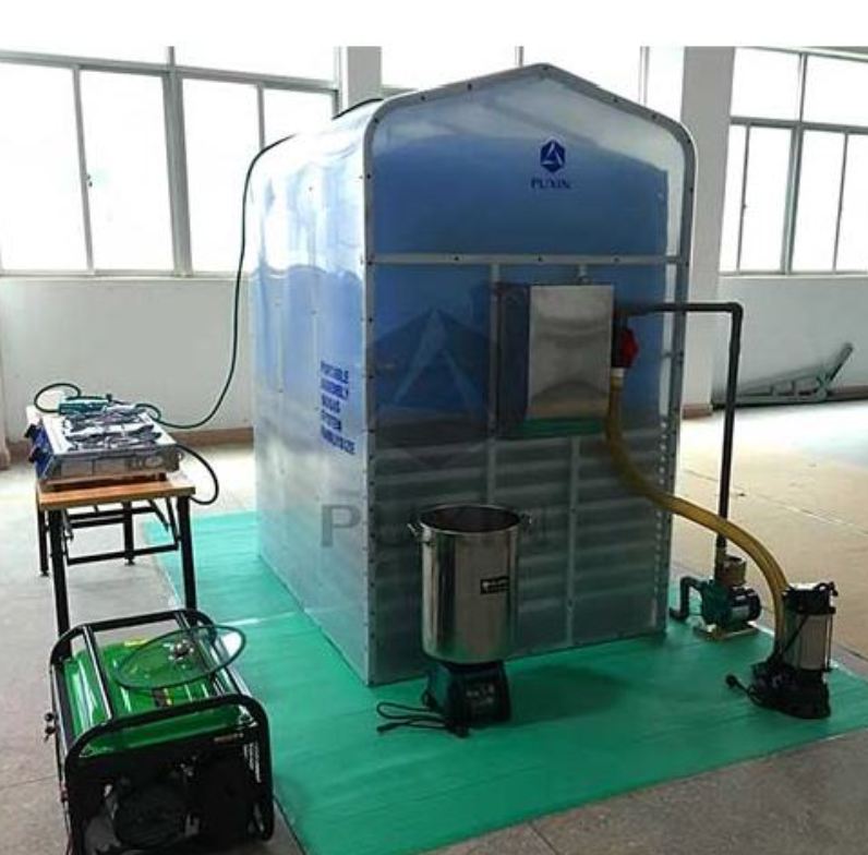 A greenhouse style frame holds a large blue bag with pipes and tubes running in and out of it. Next to this digester sits a gas burner and a generator