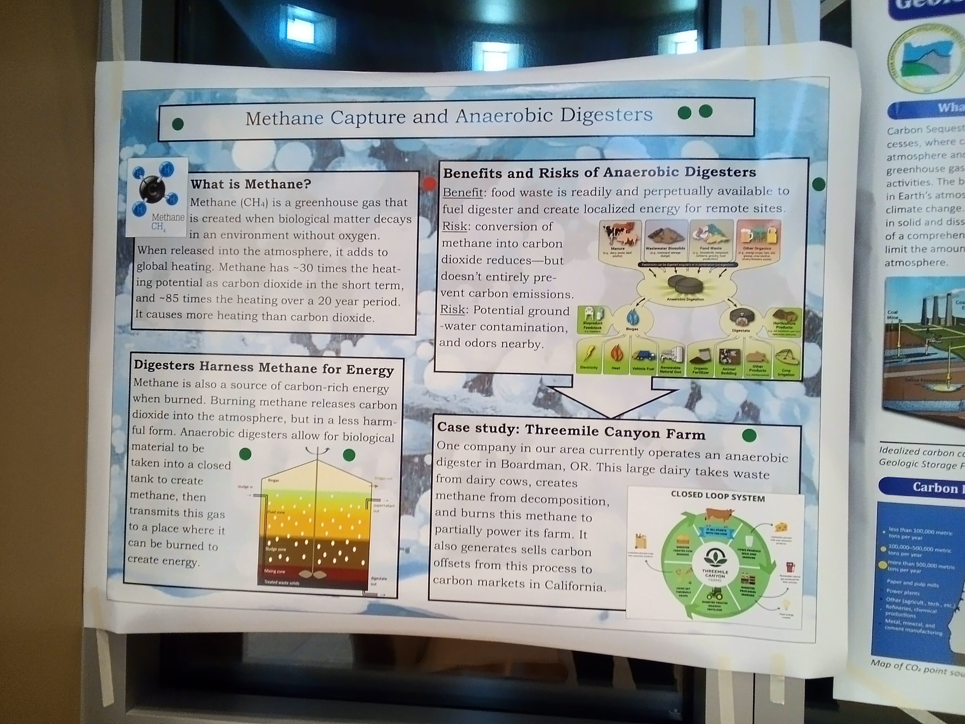 An educational poster is taped to a wall at the Nixyaawii Governance Center displaying information about methane capture and anaerobic digestion. Green dots placed around the poster indicate participants’ interest in the concept, and one red dot indicates some concerns a participant has.